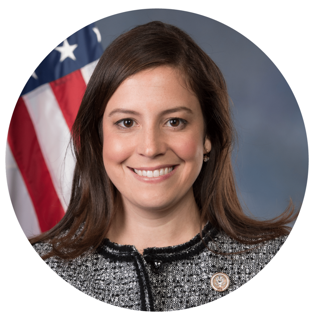 Professional headshot of Elise Stefanik, Congresswoman from New York's 21st District, House of Representatives, in front of a flag