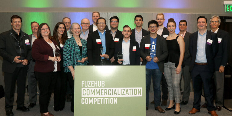 The 2018 FuzeHub Commercialization Competition participants on stage with the winners holding their trophies in the center.