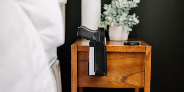 Handgun attached to a nightstand beside a bed inside the Vara Safety Lock