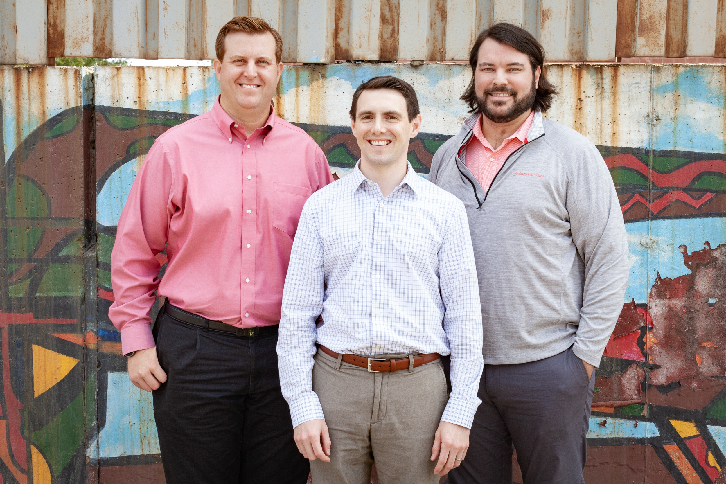 Yula Corporation employees in front of a mural painted on a rusty wall