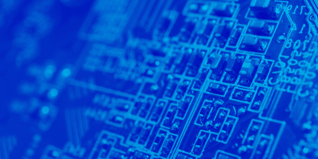 Close up blue image of a semiconductor with capacitors and printed circuits.